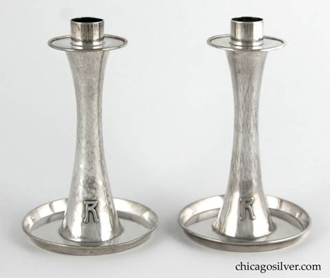 Kalo hurricane lamps, pair, composed of two candlestick bases plus two removable glass lamps.  The candlesticks have saucer-shaped bottoms with upturned rims, and taper up toward the middle then broaden out again at the top in a figure-8 shape.  The simple bobeche sits above a circular base for the glass lamps.  The tulip-shaped lamps are thin and delicate, and are covered with cut glass designs of two rows with and shapes alternating with lens-like dots.  Candlesticks have applied "R" monograms on outside of base.  Candlesticks:  3-3/4" W at bottom, 2" W at top and 6” H.  Lamps:  3-3/4" W and 6-1/2" H.  Together:  11-3/4" H.  Marked:  STERLING / HAND BEATEN / AT / KALO SHOPS / PARK RIDGE / ILLS. / 6197
