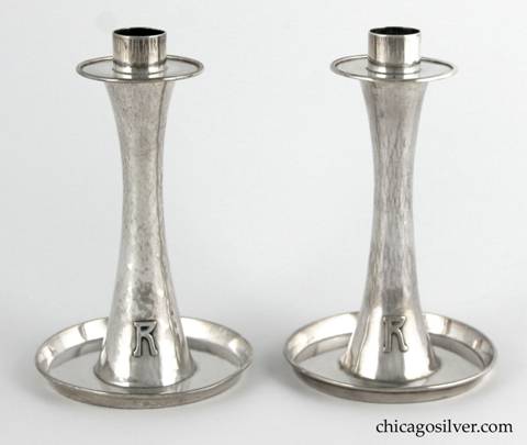 Kalo hurricane lamps, pair, composed of two candlestick bases plus two removable glass lamps.  The candlesticks have saucer-shaped bottoms with upturned rims, and taper up toward the middle then broaden out again at the top in a figure-8 shape.  The simple bobeche sits above a circular base for the glass lamps.  The tulip-shaped lamps are thin and delicate, and are covered with cut glass designs of two rows with and shapes alternating with lens-like dots.  Candlesticks have applied "R" monograms on outside of base.  Candlesticks:  3-3/4" W at bottom, 2" W at top and 6 H.  Lamps:  3-3/4" W and 6-1/2" H.  Together:  11-3/4" H.  Marked:  STERLING / HAND BEATEN / AT / KALO SHOPS / PARK RIDGE / ILLS. / 6197