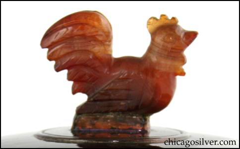 Detail from Rebecca Cauman bowl, round, copper, with removable silver lid, red-orange enameled interior and carved agate rooster finial inside small ring on lid.  