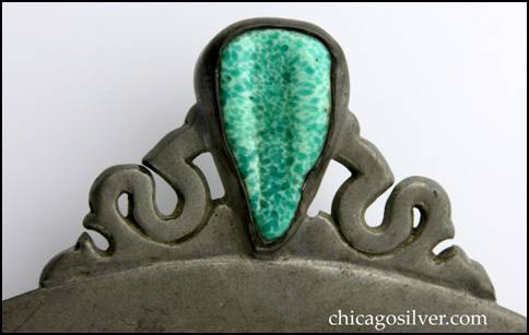 Detail from Rebecca Cauman tray, pewter, round, with two ornate curved handles, and triangular turquoise glass or ceramic insets in the handles.   