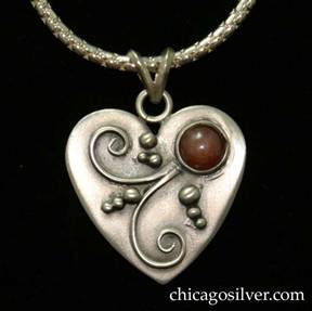 Laurence Foss pendant on chain, in the form of a small heart, with oxidized background, bead and curving wirework ornament, and bezel-set cabochon carnelian stone.