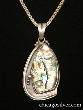 Laurence Foss pendant on chain, in a freeform teardrop shape, with an oxidized background, thick applied wire curving around on the left and bottom edges, applied beads at the top on either side of the bale ring, and a large freeform teardrop-shape bezel-set iridescent green/pink/blue paua shell in the center and right side, with a pearl inset into a small hole at the bottom of the shell, and applied beads to the left of it.  Heavy.  