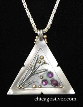 Laurence Foss pendant on chain, triangular, with fixed bale at top surrounded by three successively smaller gold beads on each side.  Wide frame with small notches in the middle of each side, around incised oxidized interior with gold beads, and detailed applied sawtooth leaves and cattails.  Three rich purple cabochon bezel-set amethyst stones at one corner.  On very thick intricate boxlike chain.