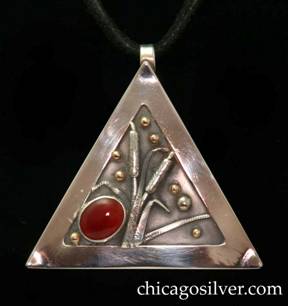 Laurence Foss pendant on cord, triangular, with fixed bale at top.  Wide silver frame around incised oxidized interior with gold beads, and detailed applied worked silver leaves and cattails.  Large diagonal oval cabochon bezel-set red stone at one corner.  On black leather cord with key-like fastener.  