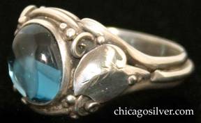 Laurence Foss ring, silver, delicate, with oval bezel-set cabochon light blue topaz stone set at a slight angle in oxidized frame surrounded by a smooth applied leaf with chased details and beads and wirework decoration on each side.  A wire runs around the back of the ring connecting the bottoms of each leaf stem.  
