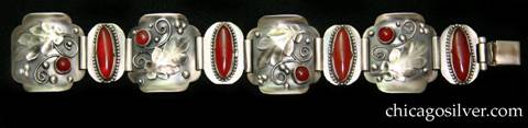 Laurence Foss bracelet, with carnelians.  Four large square convex links alternating with four smaller oval flat ones.  The large links have curved corners, and tops and bottoms that curve upward, with a large applied oak leaf, a small round cabochon bezel-set carnelian stone, and bead and curving wirework detail on each.  The small links have large oval bezel-set cabochon carnelian stones on each, with notched bezels and a thin beaded wire ornament surrounding the bezel.  Links are joined with wide silver tubes.  The piece has many Oakes-type details.