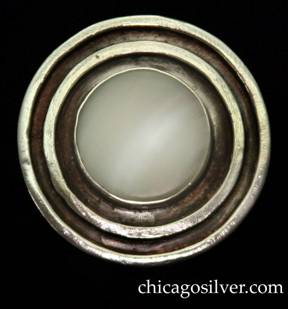 Mary Gage brooch / pin, circular frame with open back and two concentric thick rings on front centering a bezel-set mother-of-pearl disk.