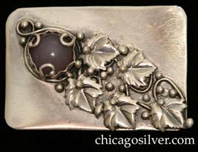 Mary Gage pin, rectangular, with rounded corners, and applied diagonal pattern of leaves, vines, and beads moving down from upper left to lower right, with a bezel-set round purple cabochon stone at top left secured by three silver loops ending with small beads