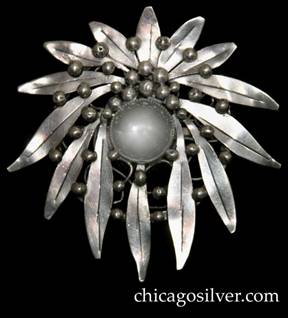 Mary Gage pin, round, composed of a wreath of long, thin outward-pointing chased leaves on a circular frame strengthened with irregular wirework beneath, centering a large clear bezel-set rock crystal stone 