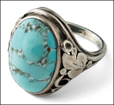 Ring by Gilbert Oakes, hand wrought in sterling silver, size 5-1/2 with a light blue turquoise cabochon with matrix (sky blue) flower, leaf, bead and scroll work on either side of shank. The right side is different from the left.  Unsigned. 