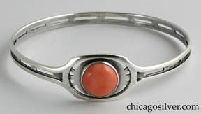 Kalo bracelet, bangle, with large oval frame centering a round bezel-set cabochon coral stone with cutouts around it and at regular intervals around the sides and back.