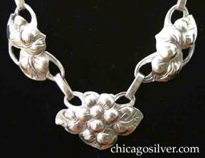 Kalo necklace, composed of 11 links ranging from round to oval, alternating single flowers with links that have three leaves on cutout frames