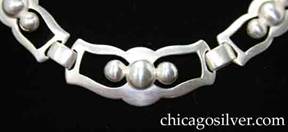 Kalo necklace, composed of nine bow-shaped links in decreasing sizes from the middle to the back, with curving cutout frames each centering a large silver dome between two small silver domes