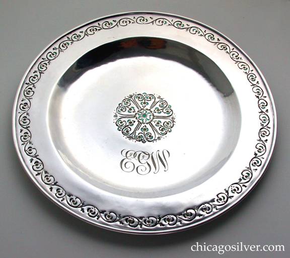 Mary Catherine Knight plate, round, enameled, with chased decoration of flowers and vines around the raised rim and in a central petal-like decoration, with green and pale yellow enamel and engraved EGW monogram in script.  