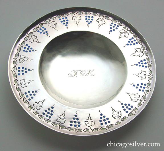 Mary Catherine Knight plate, round, enameled, on small ring foot, with chased decoration or grapes and leaves and stylized vines around the upturned edge.  Engraved FOH monogram in script at concave center.  