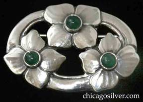 Kalo brooch / pin, oval, three large blossoms spaced evenly around a chased and cutout oval frame, each with four petals and each centering a dark green bezel-set round cabochon stone.  Lovely hammering and truly stunning.  Especially interesting because the blossoms have subtle texture lines extending from the center outward that are the result of delicate planishing rather than chasing.