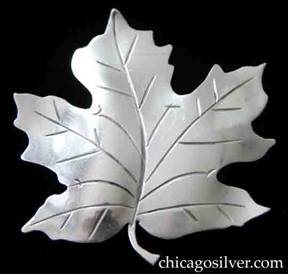 Kalo brooch in the form of a cut-out, detailed, lifelike maple  leaf, with slightly convex body, chased veins and small curving stem