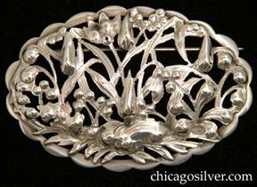 Kalo brooch, oval, unusually elaborate, with extremely complex chased, pierced, and repousse pattern of flowers, berries, and leaves, applied in one layer to a scalloped frame.  Most Kalo pins are simpler - this is the most intricate saw-pierced Kalo pin we've seen. 
