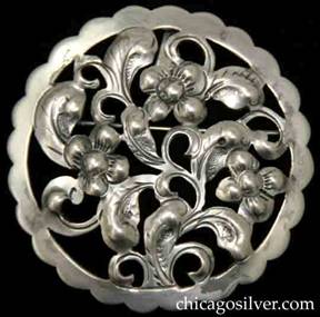 Kalo brooch, round, with scalloped edge and extensive cutout flower and leaves design.  Back has pin and loop for chain.