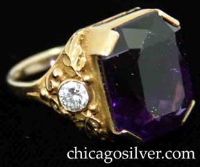 Ring, by Gilbert Oakes, handwrought in 14K gold with central faceted amethyst with deep color, flanked by bezel-set diamonds with fine, highly detailed gold work depicting leaves, scrolls and small beads.  Beautifully crafted.