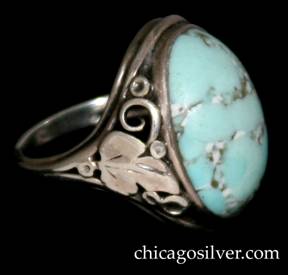 Ring, by Gilbert Oakes, handwrought in sterling silver with central, oval, light blue turquoise cabochon.  The shank has applied silver foliate and leaf ornament with beads and scrolls.  Shank is worn.