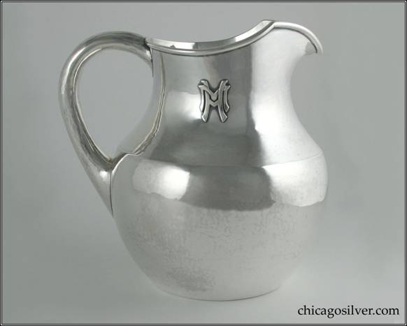 Kalo pitcher, on flat bottom, with body flaring outward from foot to just above middle, then tapering inward with narrow neck and V-shaped spout.  Applied wire to rim.  Small looping hollow handle, applied HM mono on side.  Gently hammered surfaces.  From the Estate of Mary and Frank J. Mackey, Jr.  7-1/8" W and 7-1/8" H.  STERLING / HAND WROUGHT / AT / THE KALO SHOPS / CHICAGO / AND / NEW YORK / 9317 / 4 PTS