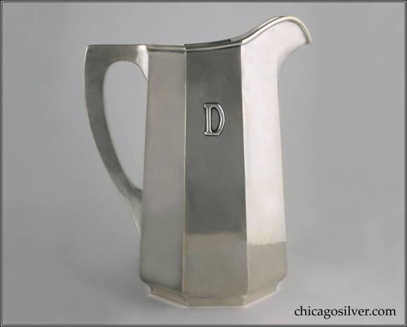 Kalo pitcher, water, tall tapered paneled form on low self-foot with applied "D" mono, arching spout, heavy wire applied to rim, and harp-shaped square-section hollow handle with flat top.  Nicely hammered surfaces.  Heavy.  With original green cloth Kalo bag.  (Note:  Bag has curious spelling of Silverware:  "The Kalo Shop / Makers of Hand Wrought / Silverwear and Jewelry / Chicago".)  Pitcher:  9-5/8" H and 7-3/4" W.  Bag:  14-3/4" W and 14" H (closed).  STERLING / HAND WROUGHT / AT / THE KALO SHOP / G574L