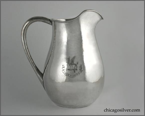 Kalo water pitcher with high looping hollow handle, and applied W / 1884 1909 monogram, engraved dragon and "FORTITUDE" on side.  Flat bottom.  Nicely hammered.  Beautiful, fluid shape with attractive spout.  8-3/4" W across handle and 10" H.  STERLING / HAND BEATEN / AT / KALO SHOPS / PARK RIDGE / ILLS.