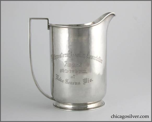 Kalo pitcher, trophy, with cylindrical body, high spout, on wide foot, with angled, curving strap handle, engraved "First Prize / Class D / Presented by the / Lake Geneva Yacht Club / Won by" on one side, "Northwestern Regatta Association / August / 8th to 12th 1911. / at / Lake Geneva Wis." on other.  6-1/2" H and 6" W.  STERLING / HAND BEATEN / AT / KALO SHOPS / PARK RIDGE / ILLS. / 9301