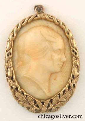Potter Studio pendant, gold, oval wreathlike frame of leaves and ribbons, thicker at the bottom, centering ivory cameo of woman facing right, with hair pulled back.  With loop at top for chain.  Heavy.