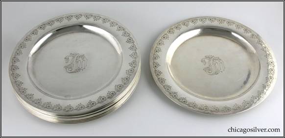 Kalo plates, dinner, set of twelve (12), with deeply chased flowers around outside and a "JFM" monogram in center on front