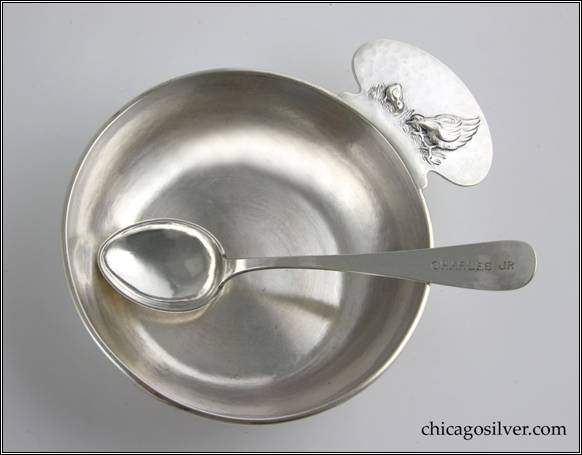 Kalo porringer with applied wire to rim and rounded tab handle with chased and repoussé decoration of hen and chick standing on grass, engraved "CHARLES JR" on side.  Matching spoon with heart-shaped bowl and rounded end, with engraved "CHARLES JR" on end