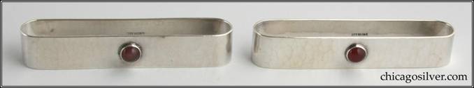 Kalo napkin rings, pair, (2), with stones.  With oval ends, nicely hammered surfaces, and a round bezel-set red cabochon stone on the back of each.  One is engraved "Dean" and the other "Sade" in script on the front.  3-3/8" L and 5/8" D (not incl. stone) and 5/8" H. Marked:  STERLING / KALO.  Kalo napkin rings are fairly common, but these are the only ones with stones we've ever seen.