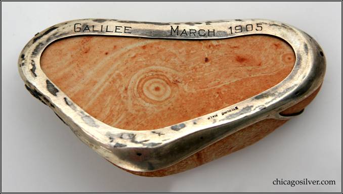 Kalo paperweight / souvenir, stone  encompassed within silver wirework frame of leaves and vines with chased details.  Engraved on bottom "GALILEE    MARCH 1905" 4" L and 2-1/4" W and 1-1/8" H.  Marked:  STERLING KALO.  The oldest inscribed Kalo object in our collection.