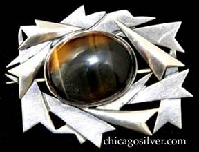 Art Silver Shop brooch / pin, made of overlapping cutout and applied arrowhead forms on a complex cutout frame centering a large oval bezel-set cabochon tigers-eye stone.