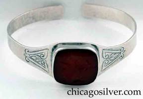 Art Metal Studios bracelet, with large intaglio carnelian stone, open back and tapering rounded ends.  Stone is bezel-set with profile of helmeted Greek or Roman soldier.  Chased design on both sides of stone.  Hammered surface.