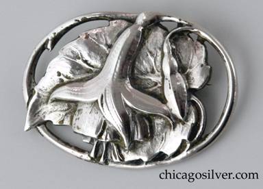 Peer Smed brooch / pin, on open oval frame, with chased blossom and seed pod atop large detailed leaf whose pointed end extends slightly past the edge of the frame.