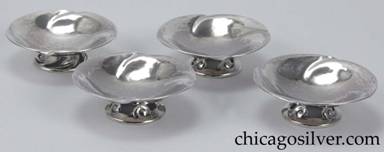 Peer Smed salts, set of four (4), round bowls with four evenly-spaced repouss swirling decorations at the edge, on small spreading cutout feet that repeat the swirling form.