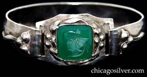 Bracelet, with concave curving back attached to octagonal front piece with hooked ends through slots.  Front has green translucent square bezel-set stone with intaglio carving of Hermes.  Very nicely chased and hammered applied flowers and leaves around stone and on front ends of curving back.