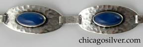 Bracelet made of four oval convex links centering bezel-set lapis cabochon stones, with long silver loops connecting them.  Hammered surfaces.  